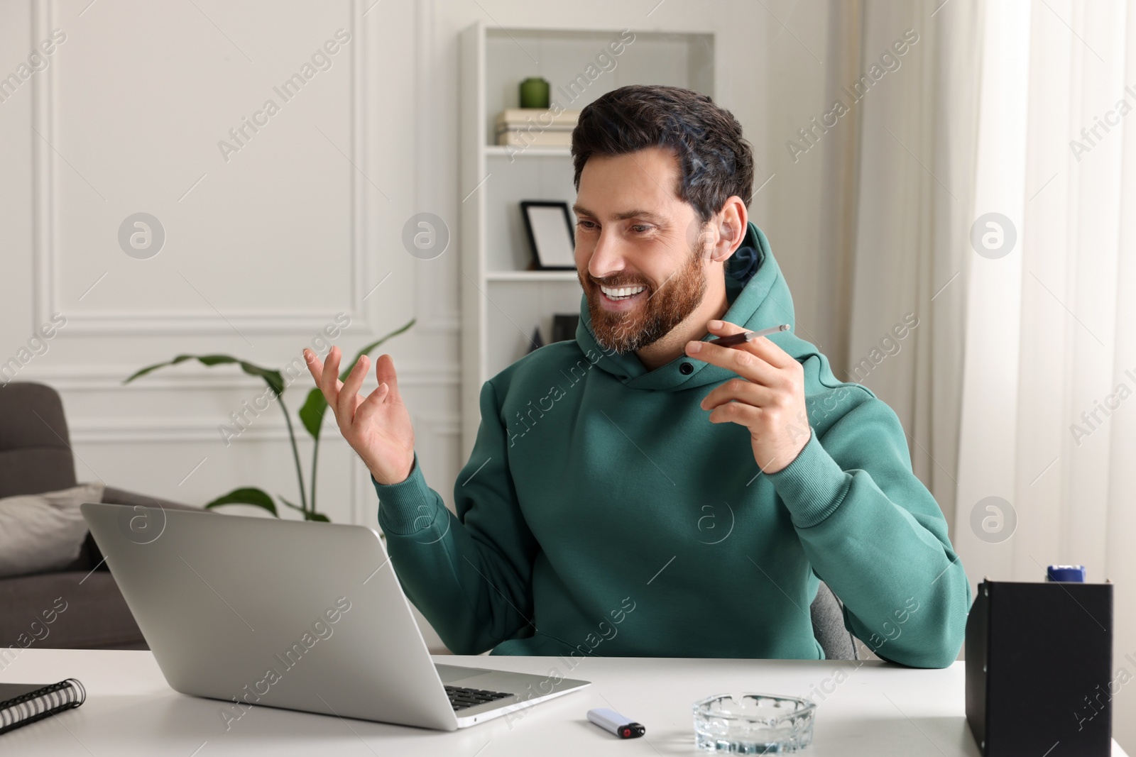 Photo of Man using cigarette holder for smoking at workplace in office