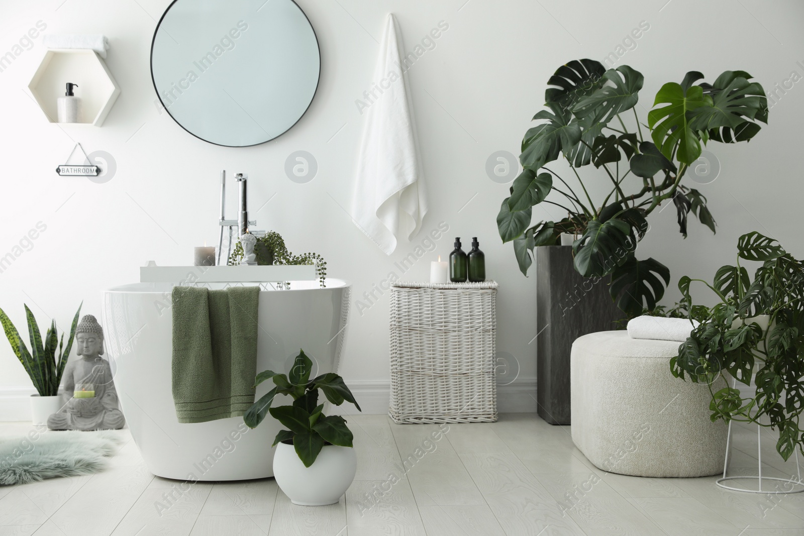 Photo of Stylish bathroom interior with modern tub, houseplants and beautiful decor. Home design