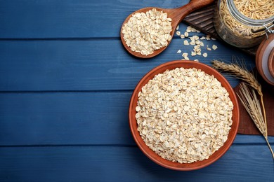 Photo of Bowl of oatmeal and spikelets on blue wooden table, flat lay. Space for text