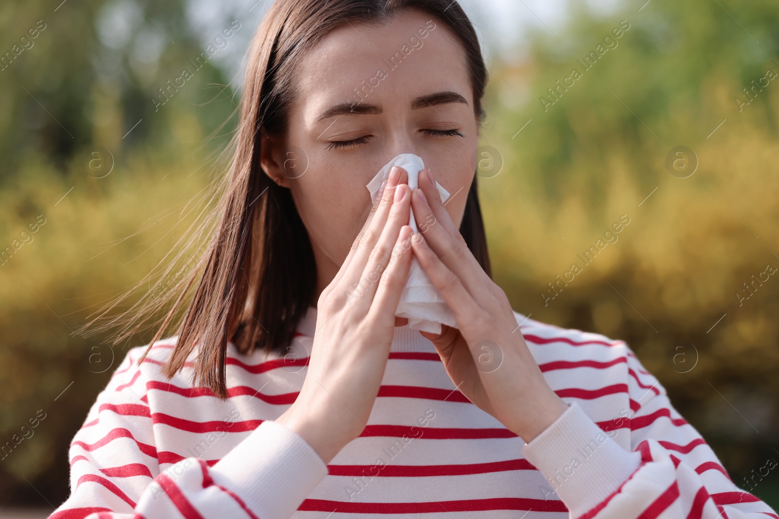 Photo of Woman with napkin suffering from seasonal allergy outdoors