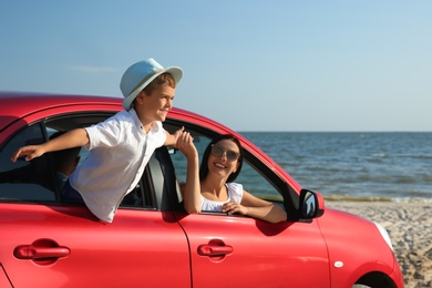Photo of Happy woman and her son in car near sea. Summer trip