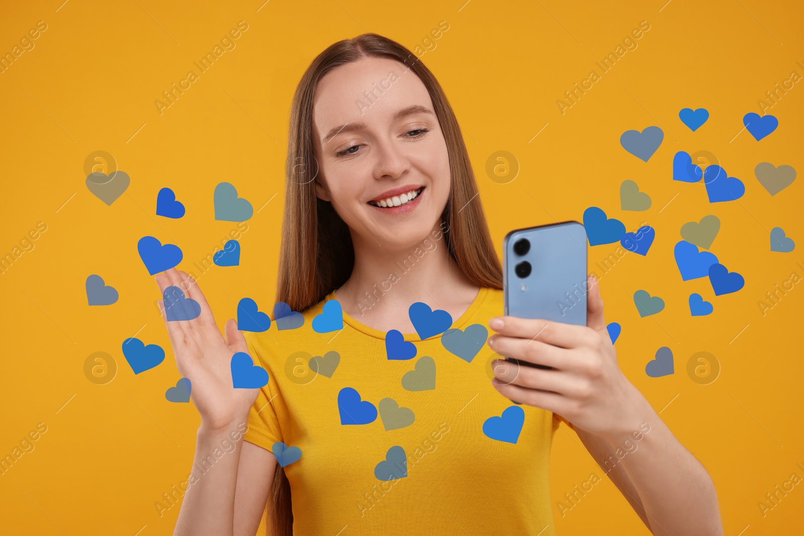 Image of Long distance love. Woman video chatting with sweetheart via smartphone on golden background. Hearts flying out of device