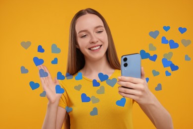 Image of Long distance love. Woman video chatting with sweetheart via smartphone on golden background. Hearts flying out of device