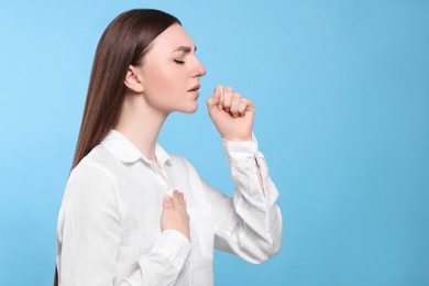 Photo of Young woman coughing on light blue background, space for text. Sore throat