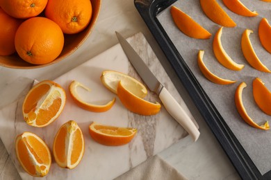 Photo of Fresh orange peels and slices of fruits on white table, flat lay