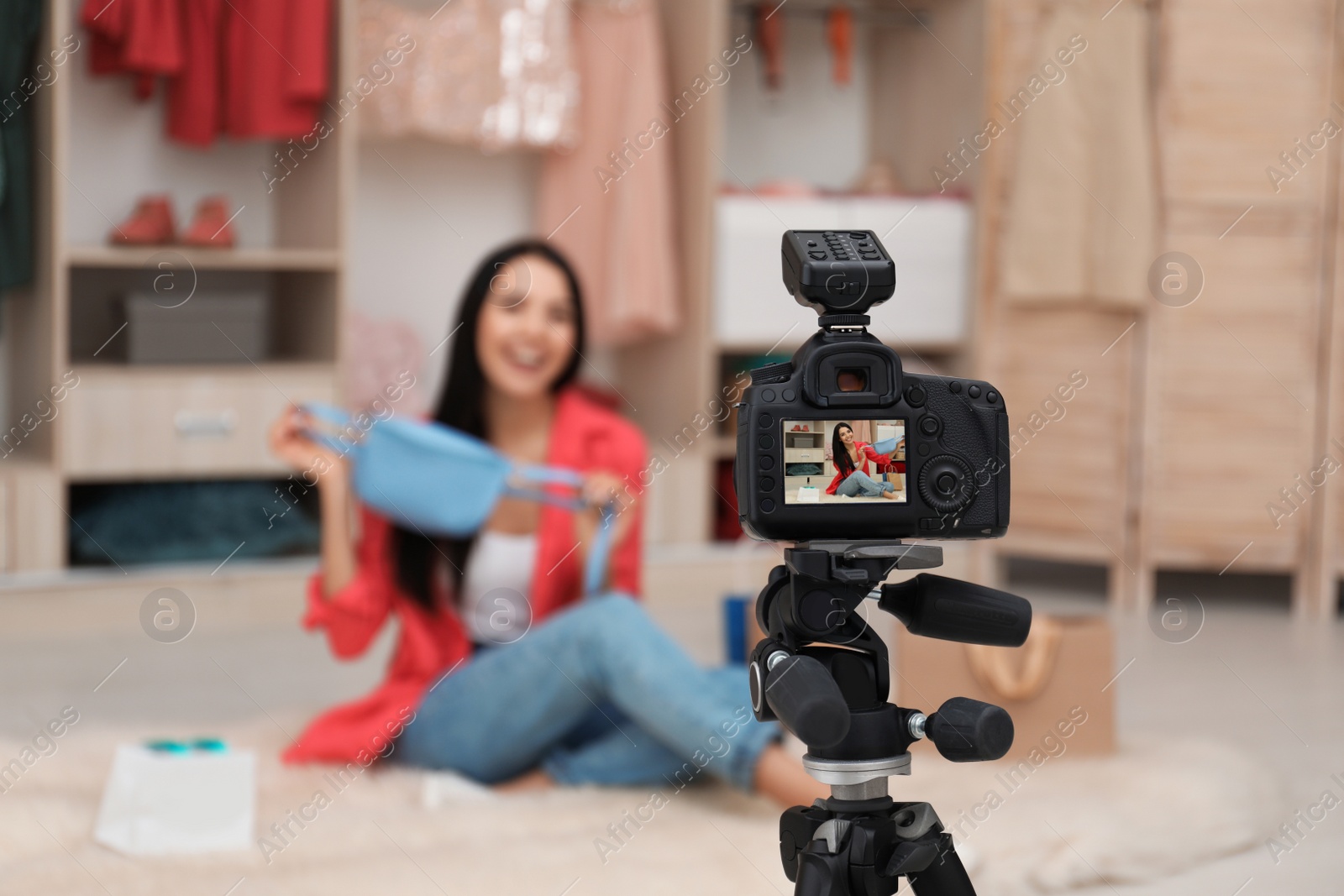 Photo of Fashion blogger recording new video in room, focus on camera