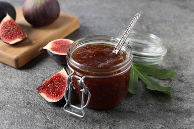 Jar of tasty sweet jam and fresh figs on grey table