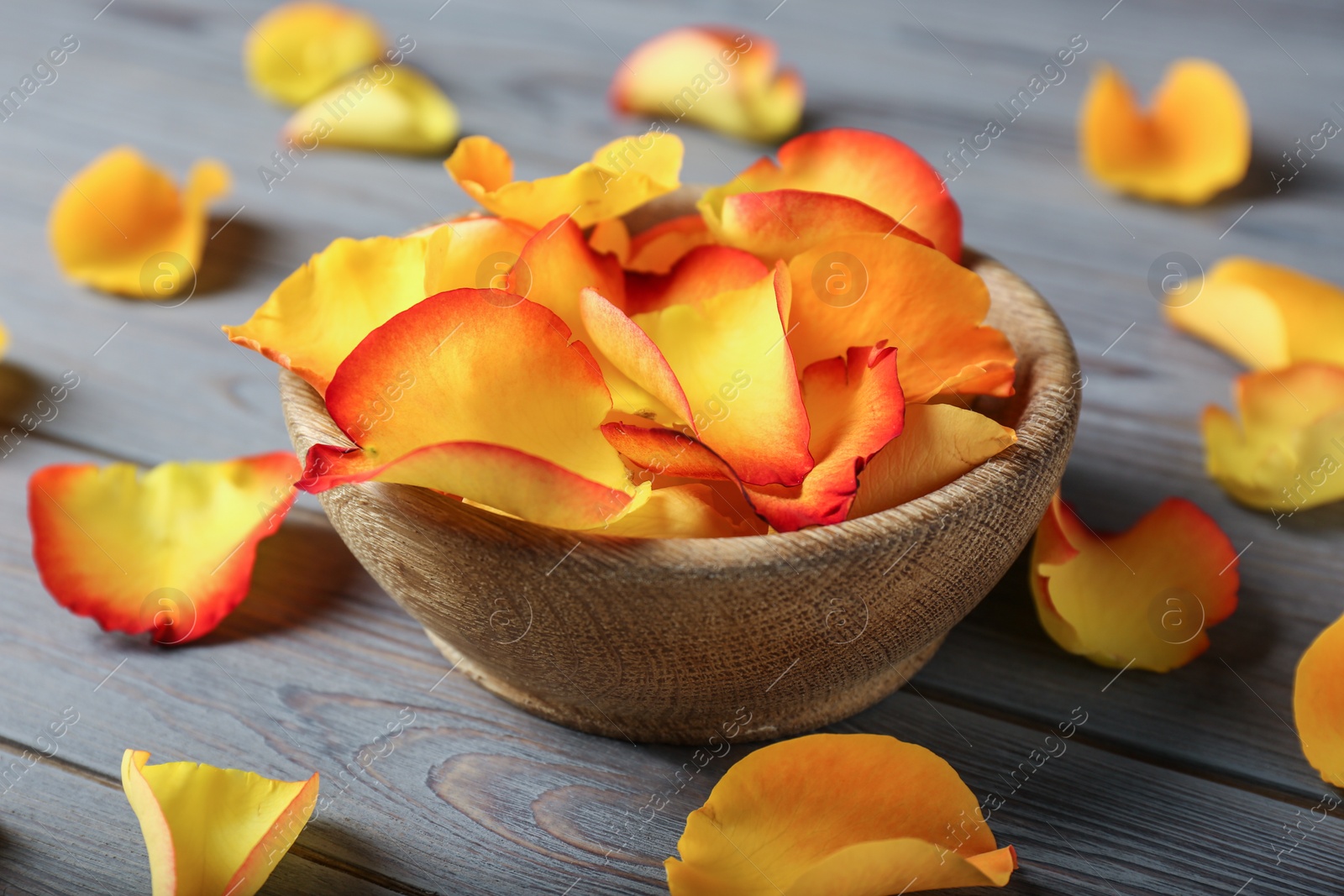 Photo of Bowl with rose petals on wooden background