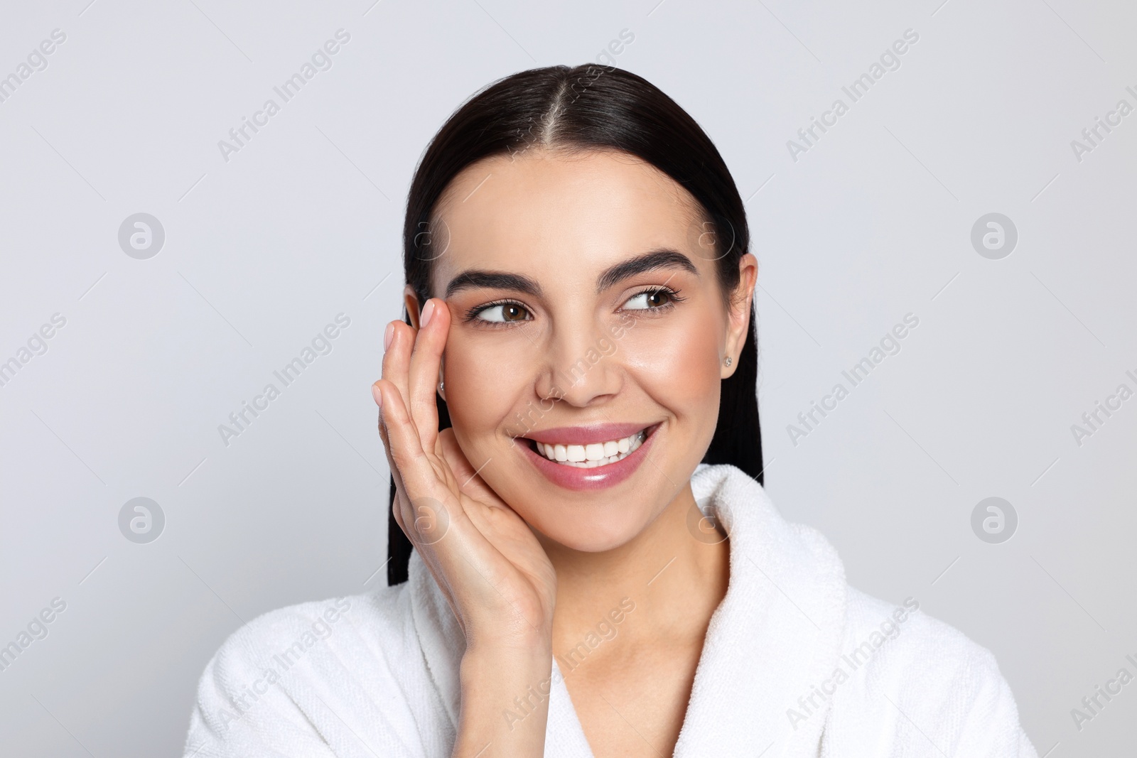 Photo of Portrait of attractive young woman in bathrobe on light grey background. Spa treatment