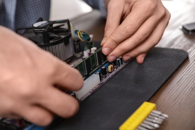 Photo of Male technician repairing motherboard at table, closeup