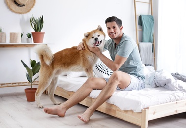 Man and Akita Inu dog in bedroom decorated with houseplants