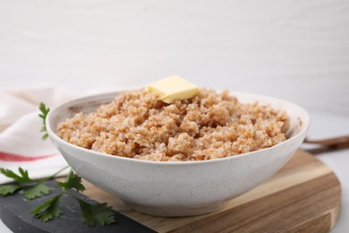 Photo of Tasty wheat porridge with butter and parsley in bowl on table, closeup