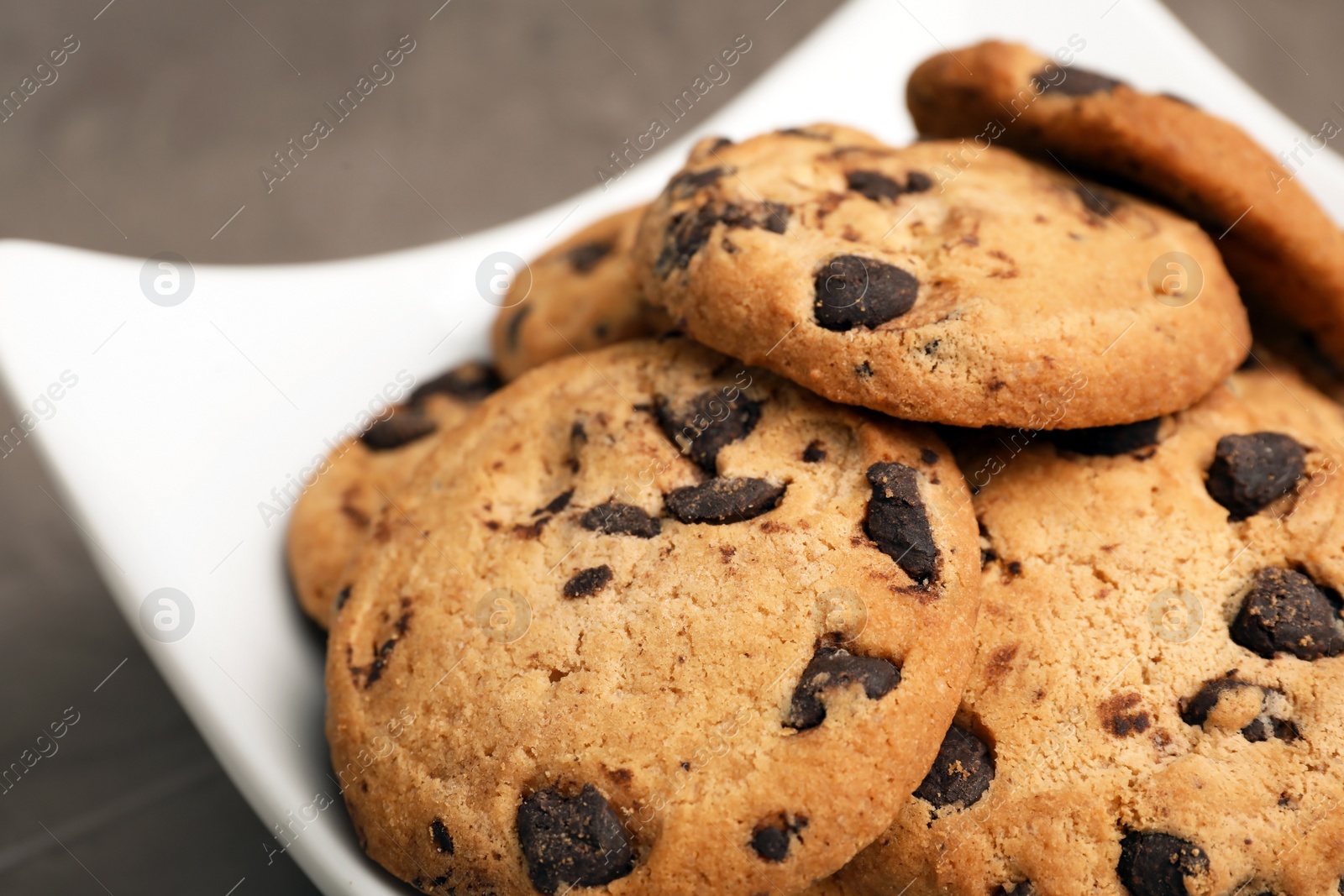 Photo of Plate with chocolate chip cookies on grey background, closeup