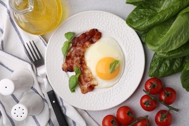 Photo of Fried egg and bacon served on light grey table, top view