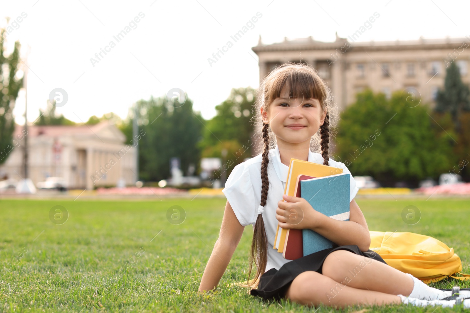 Photo of Schoolgirl with stationery sitting on grass outdoors