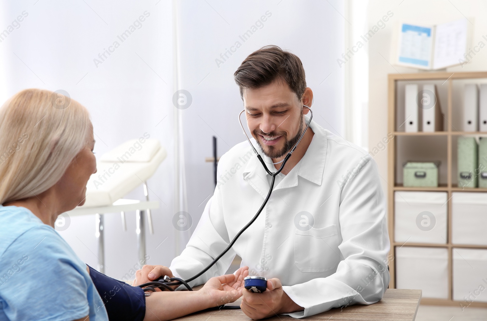 Photo of Mature woman visiting doctor in hospital. Measuring blood pressure and checking pulse