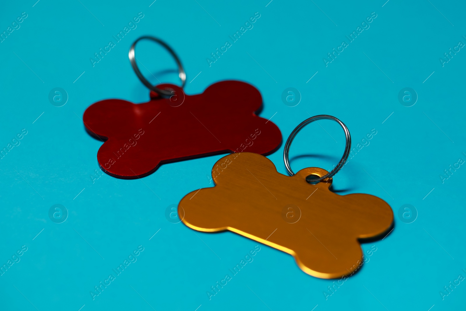 Photo of Color metal pet tags with ring on light blue background, closeup. Space for text