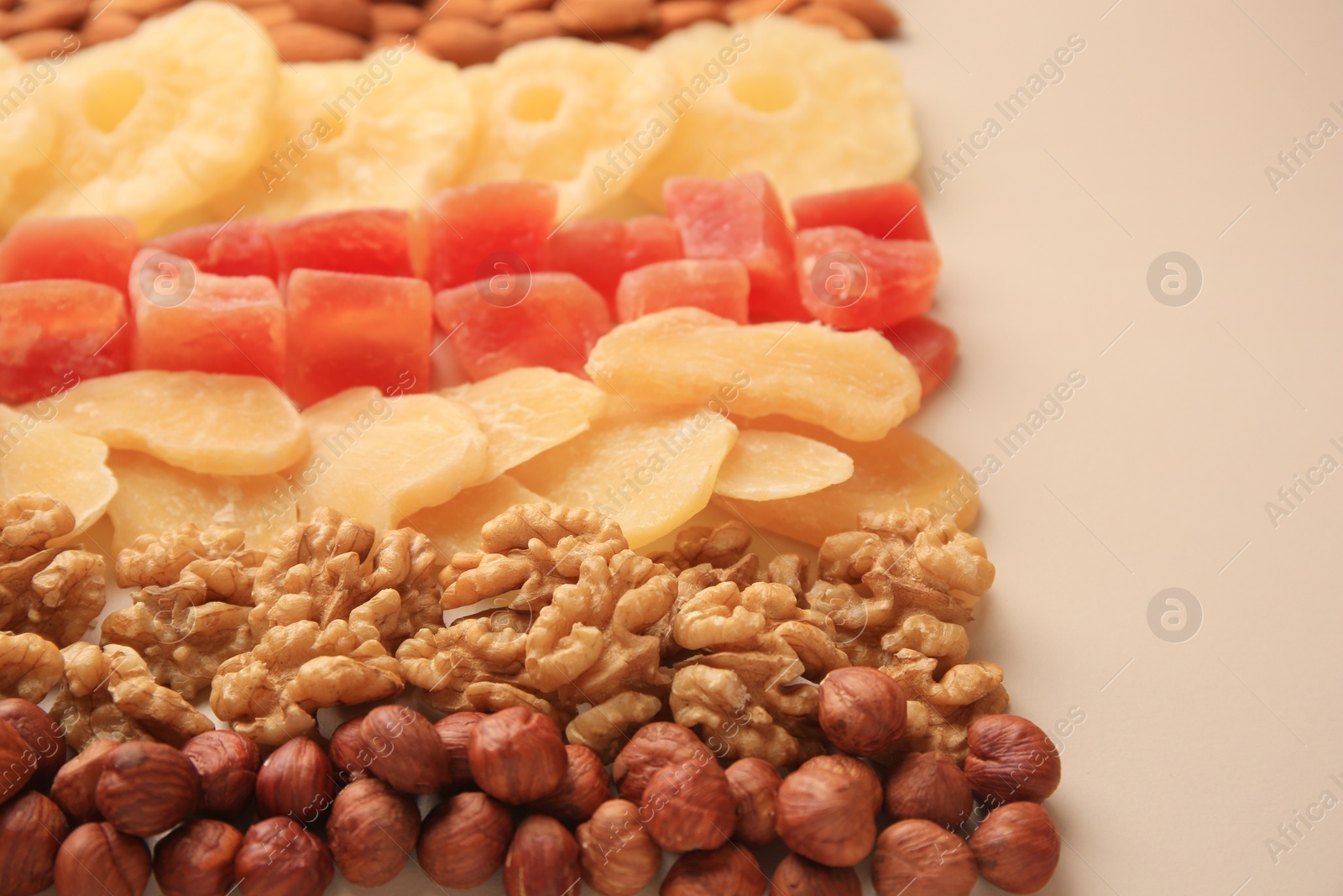 Photo of Different tasty nuts and dried fruits on beige background