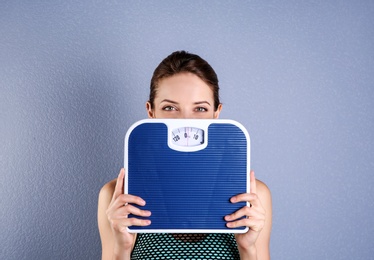Photo of Young beautiful woman with scales on color background. Weight loss motivation