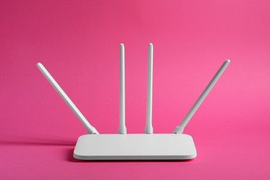 Photo of New white Wi-Fi router on pink background