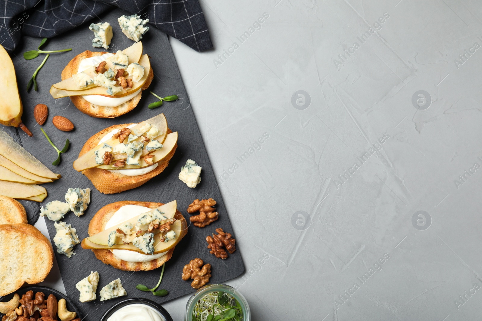 Photo of Delicious bruschettas with cheese, pear and nuts on grey table, flat lay. Space for text