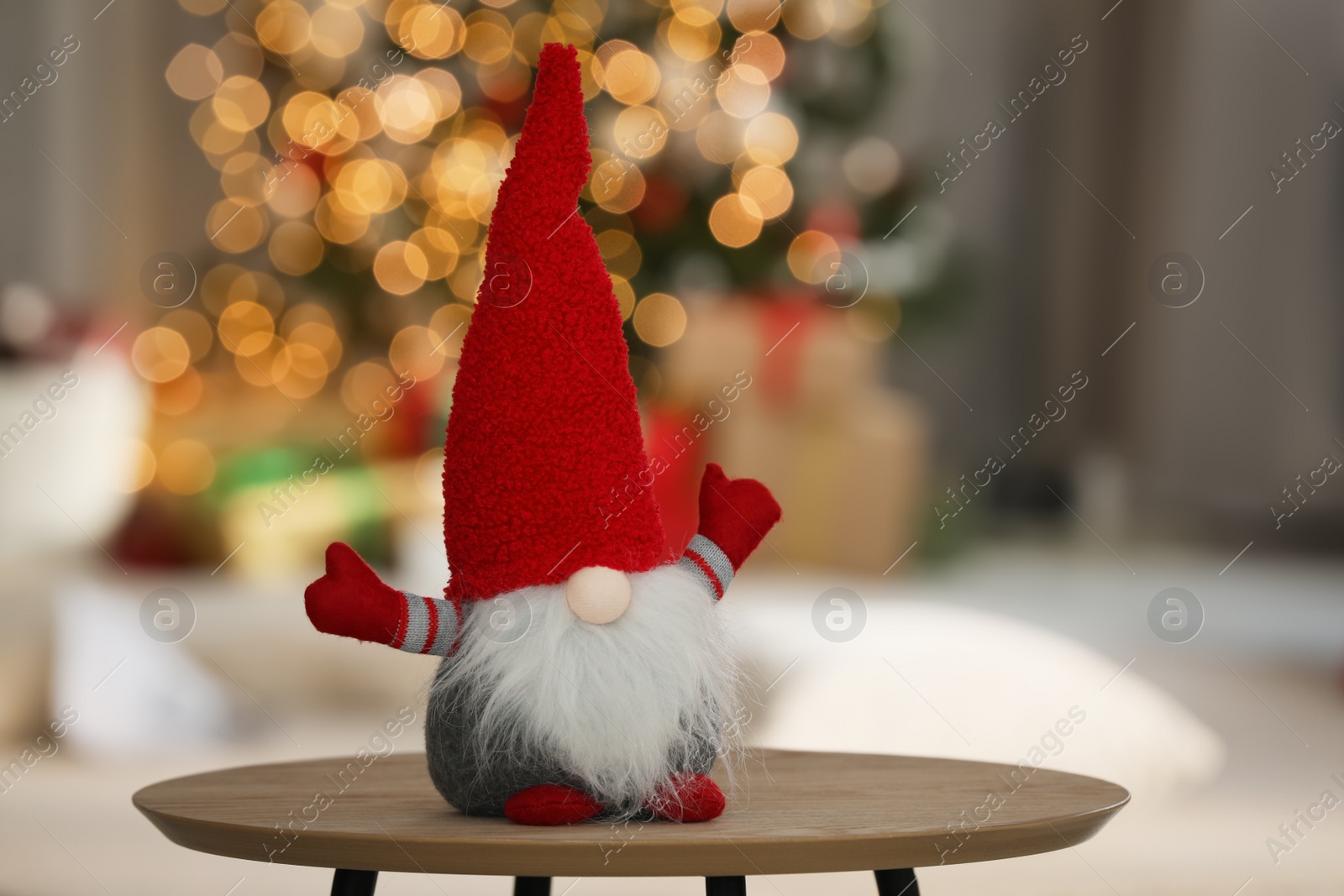 Photo of Cute Christmas gnome on wooden table in decorated room, space for text