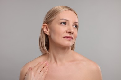 Photo of Beautiful woman touching her neck on grey background