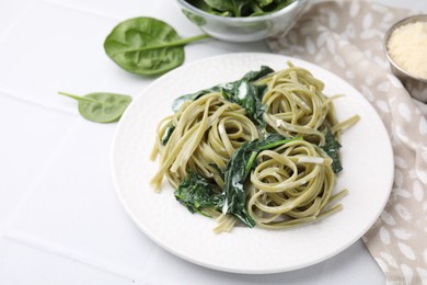 Photo of Tasty pasta with spinach and sauce on white tiled table