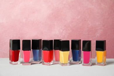 Photo of Bright nail polishes on table against color background. Space for text