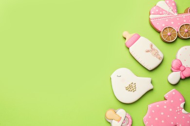 Cute tasty cookies of different shapes on light green background, flat lay with space for text. Baby shower party