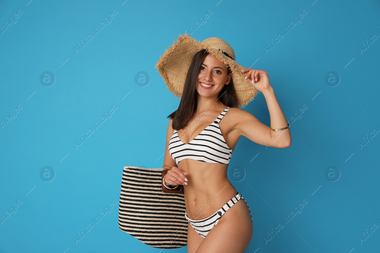 Photo of Pretty sexy woman with slim body in stylish striped bikini on blue background. Space for text