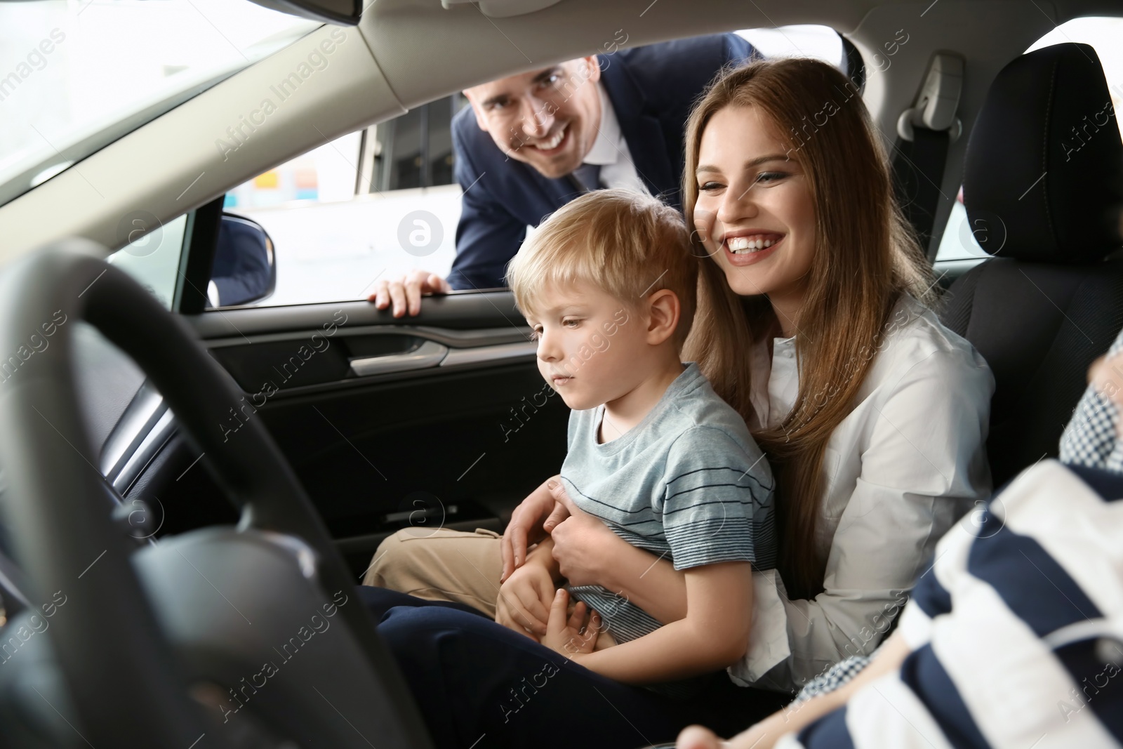 Photo of Young family choosing new car with salesman in salon