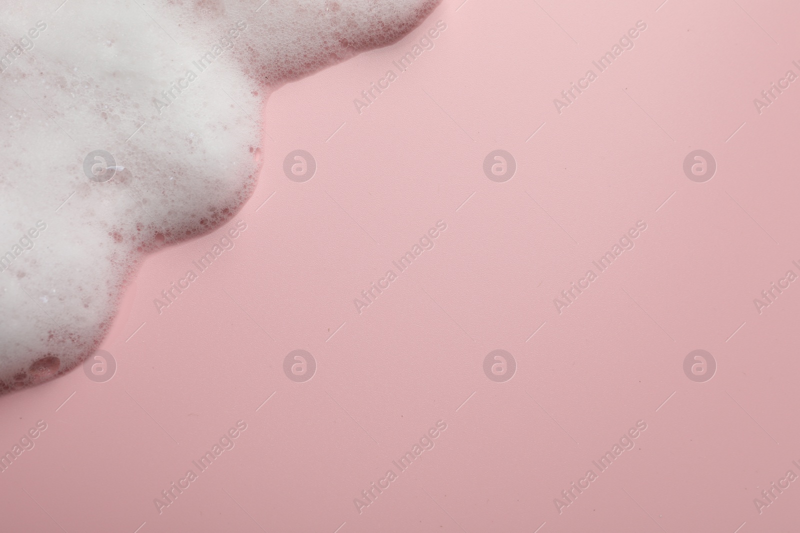 Photo of Fluffy soap foam on pink background, top view. Space for text