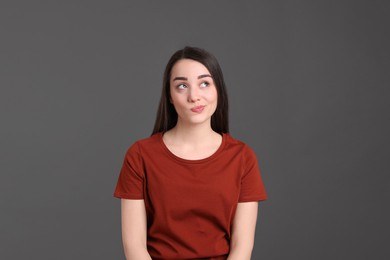 Photo of Portrait of emotional young woman on dark grey background. Personality concept