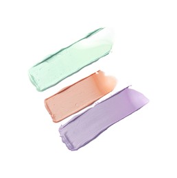 Photo of Strokes of pink, green and purple color correcting concealers on white background, top view