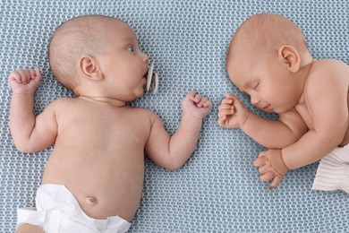 Adorable newborn twins on blue knitted blanket, above view