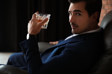 Photo of Young man with glass of whiskey indoors