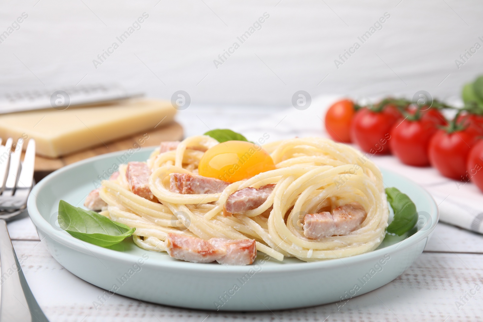 Photo of Delicious pasta Carbonara with egg yolk on white wooden table, closeup