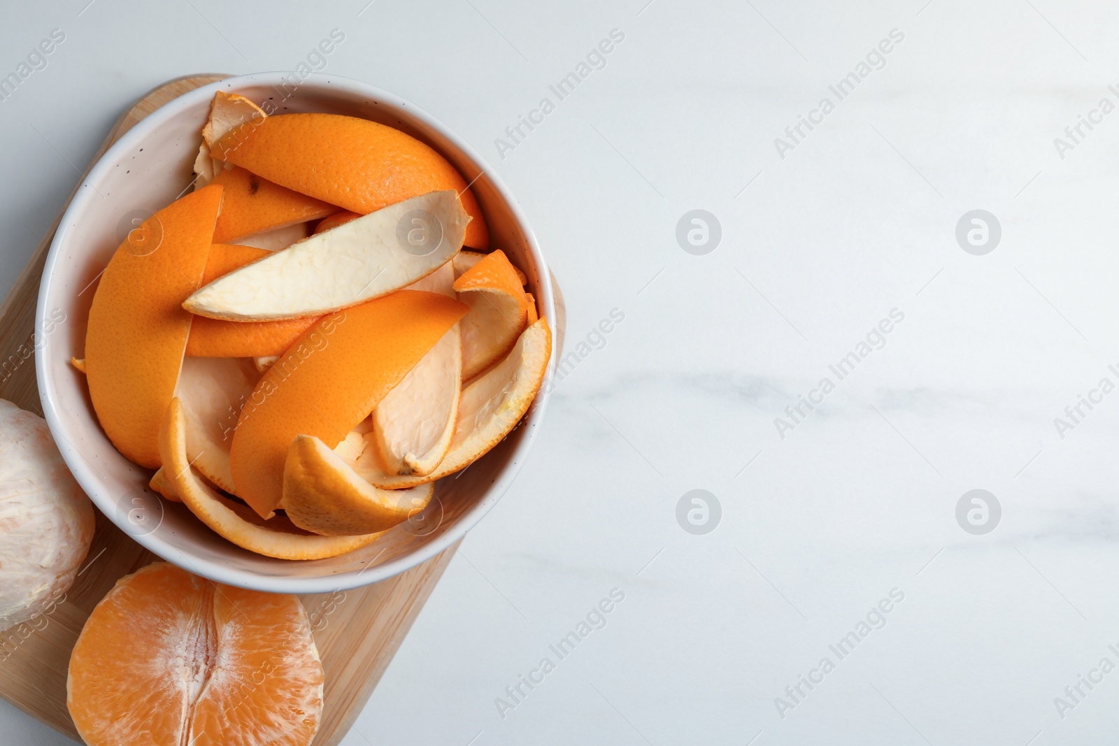 Photo of Peeled fresh fruits and orange zest preparing for drying on white marble table, top view. Space for text