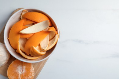 Photo of Peeled fresh fruits and orange zest preparing for drying on white marble table, top view. Space for text