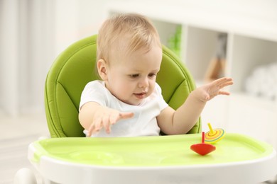 Children toys. Cute little boy playing with spinning tops in high chair at home