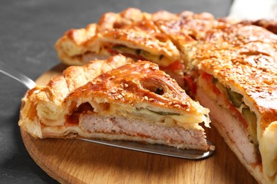 Photo of Cut delicious homemade pie and server on black table, closeup