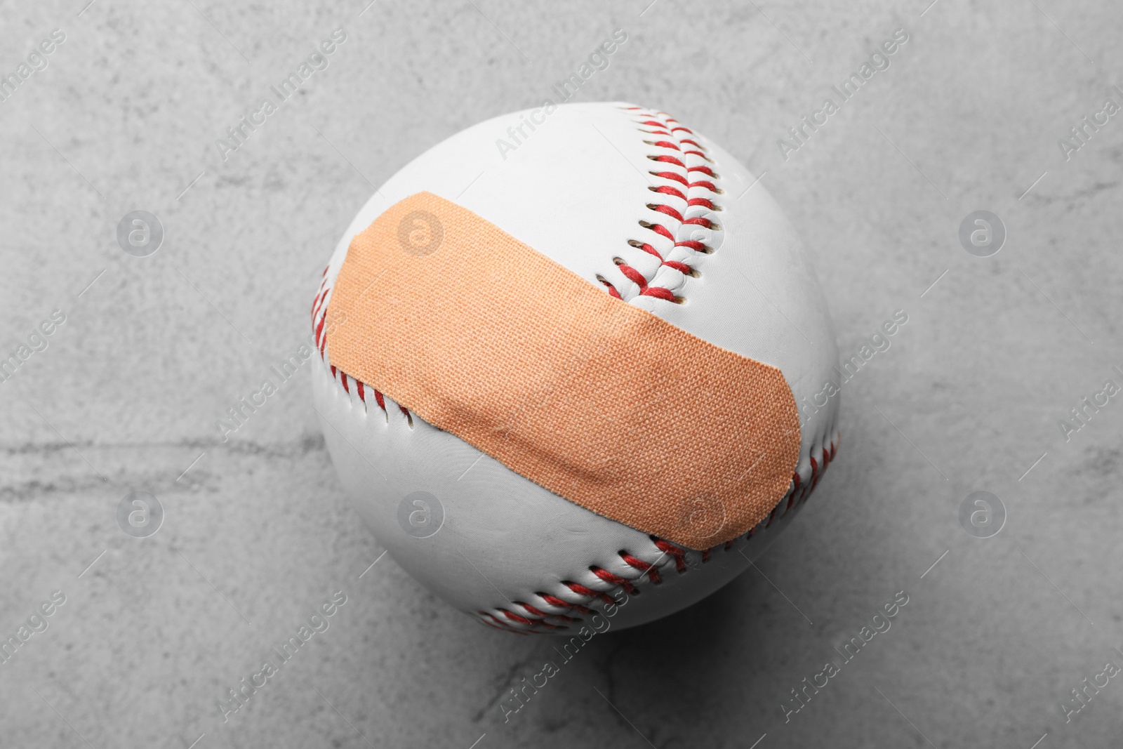 Photo of Ball with sticking plaster on light grey stone table, top view