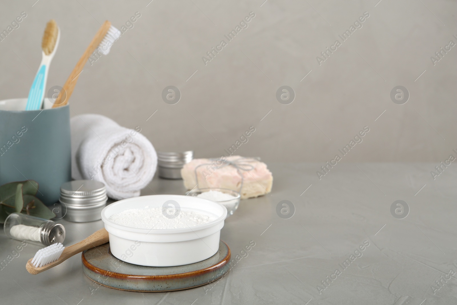 Photo of Composition with tooth powder and brushes on grey table, space for text