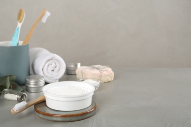 Photo of Composition with tooth powder and brushes on grey table, space for text