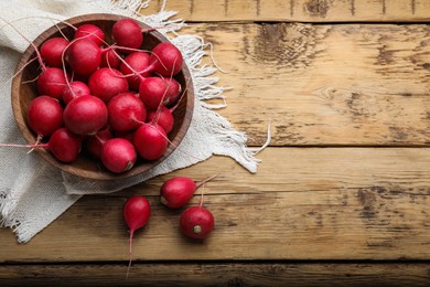 Photo of Bowl with fresh ripe radishes on wooden table, flat lay. Space for text