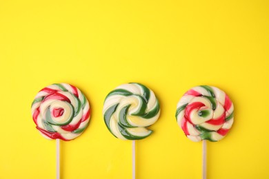 Photo of Colorful lollipops on yellow background, flat lay. Space for text