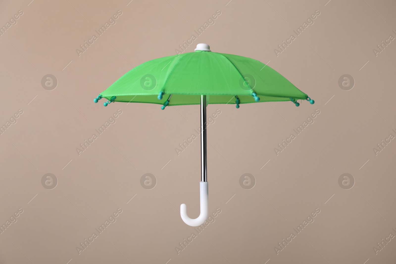 Photo of Open small green umbrella on beige background