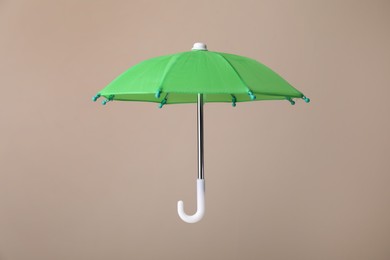 Photo of Open small green umbrella on beige background