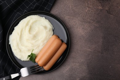 Photo of Delicious boiled sausages, mashed potato and parsley on brown table, top view. Space for text